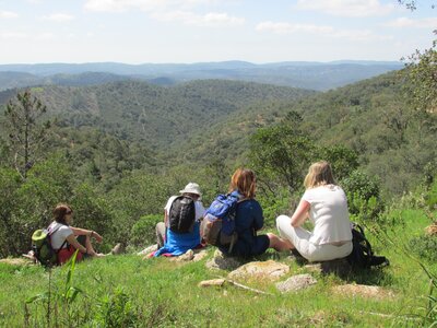 Group of walkers sat on hill enjoying view of mountainous landscape, Algarve, Portugal