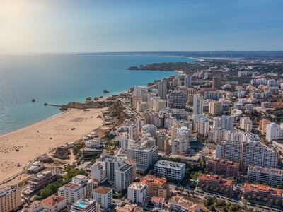 Portimao cityscape with golden beach and blue sea stretching into distance, Algarve, Portugal