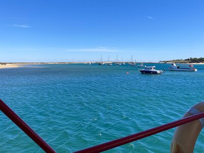 Boat ride to Tavira Island depicting blue sky and waters with small boats floating in distance, Algarve, Portugal