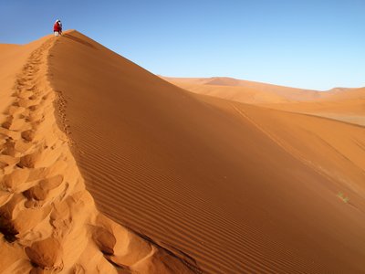 Tourist walking up a dune in Sossusvlei, Namib Naukluft National Park, Namib desert, Namibia