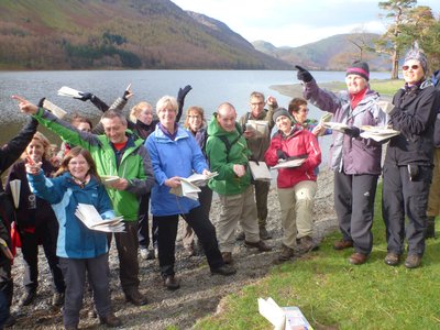 Navigation & Hill Skills group standing by Buttermere Lake holding maps and pointing in different directions