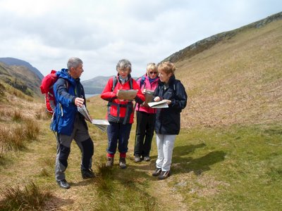 Group of 4 hikers looking at map using orienteering skills