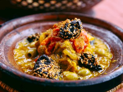 Close up of Moroccan meal lamb tagine with prunes coated in roasted sesame seeds