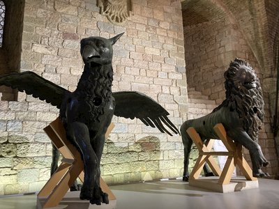 Metal griffin statue and lion statue showcased in well-lit natural lighting brick building, Perugia, Italy