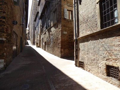 Long alleyway in Mezzogiorno with sunlight shining through, Urbino, Italy