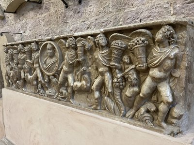 Historic stone artwork depicting people holding items, Gubbio, Italy