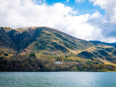 Hassness House shown in distance across Buttermere Lake with fells in background, Lake District, Cumbria
