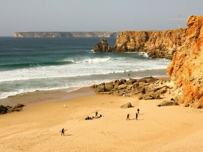 Distant view of surfers preparing themselves on the golden sandy beach at Sagres, Algarve, Portugal