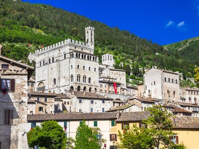 Buildings surrounding Palazzo dei Consol with green mountains in background, Gubbio, Umbria, Italy