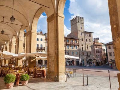 Seating area with building viewed from between arch, Piazza Grande, Arezzo, Val di Chiana, Arezzo district, Tuscany, Italy