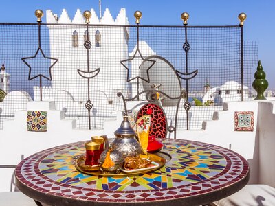 Rooftop tea service with traditional Moroccan tea placed on mosaic table on terrace in the kasbah of Tangier, Morocco