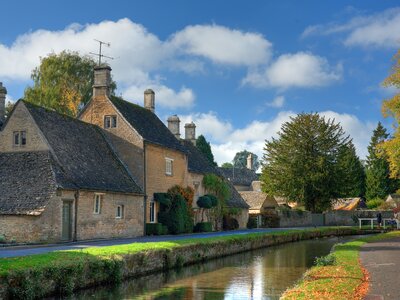 Slow river passing near houses of Cotswold Village, Gloucestershire, England
