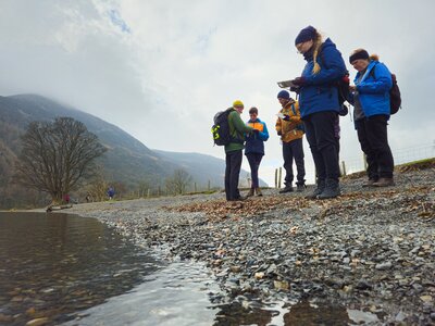 Ramble Worldwide Navigation skills course group map reading on Buttermere Lake shore, Lake District, Cumbria