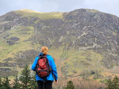 Female hiker looking at Robinson mountain peak in distance from Buttermere, Lake District, Cumbria